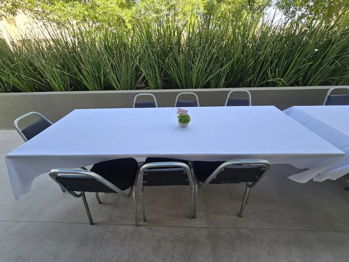 Sillas plegables acojinadas negras alrededor de mesa con mantel en jardín